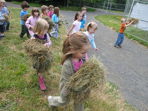 Children carrying bundles of hay