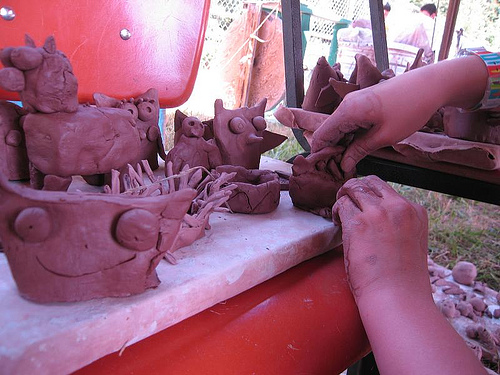 Clay pieces on a chair with someone reaching in to fix something on a clay piece