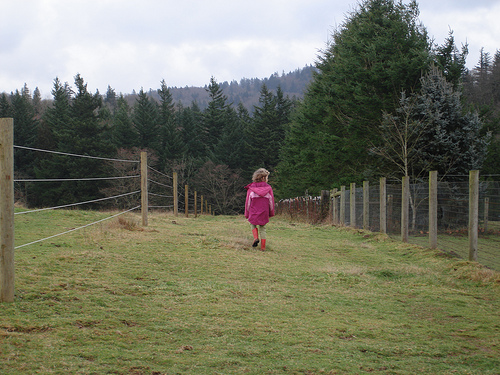 Little girl walking in a meadow with her pink boots on.