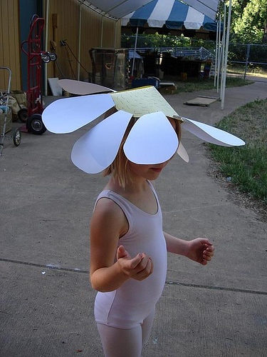 A child with a giant daisy on her head
