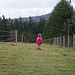 Little girl walking in a meadow with her pink boots on.