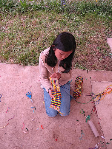 A child weaving a rainbow weaving.